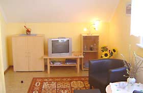 Wohnbereich mit Fernseher und Sesseln in der Ferienwohnung