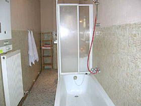 betegelde badkamer met bad, douchegelegenheid en wasmachine