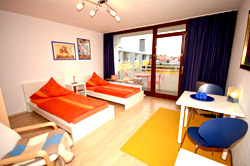 Das Appartement in München, Schlaf/Wohnzimmer mit zwei Einzelbetten, Balkon und einer Sitzmöglichkeit