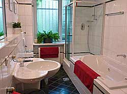 La grande salle de bains avec baignoire et douche