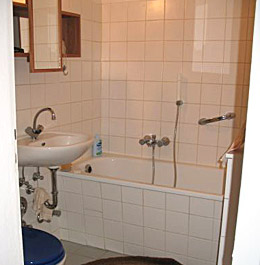 Betegelde badkamer met ligbad en douche-voorzieningen