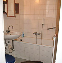 Gefliestes Bad mit Badewanne und Duschmöglickeit