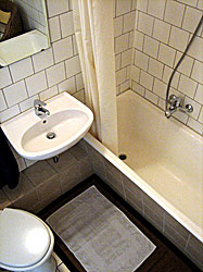 выложенная плиткой ванная комната с ванной