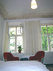 Duże podwójne łóżko oraz wygodne krzesła w sypialni - Berlinie Prenzlauer Berg